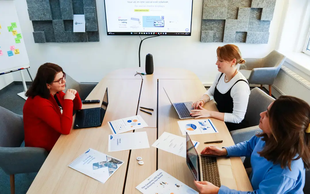 três mulheres em sala reunião com laptops