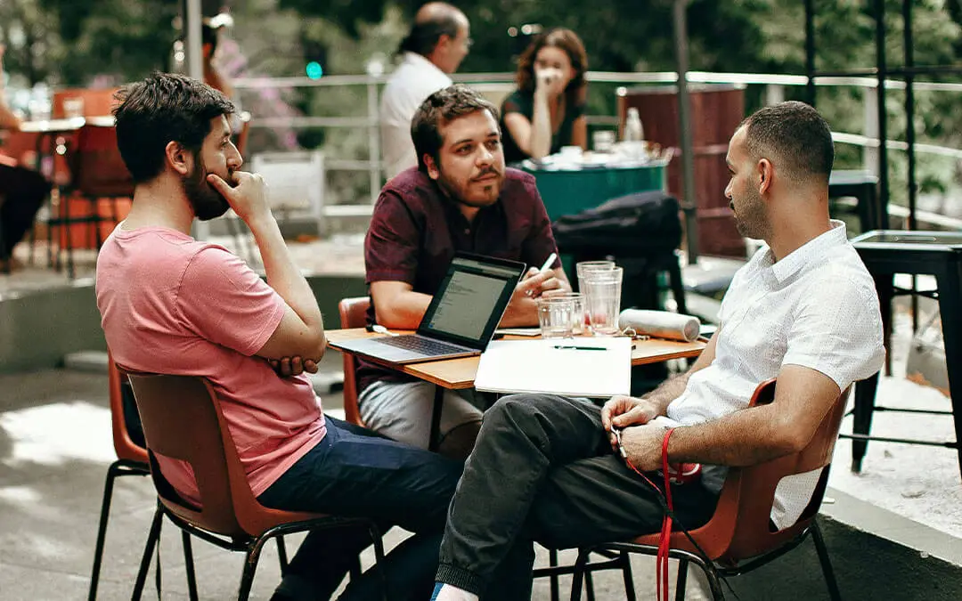 homens conversando em mesa de cafeteria