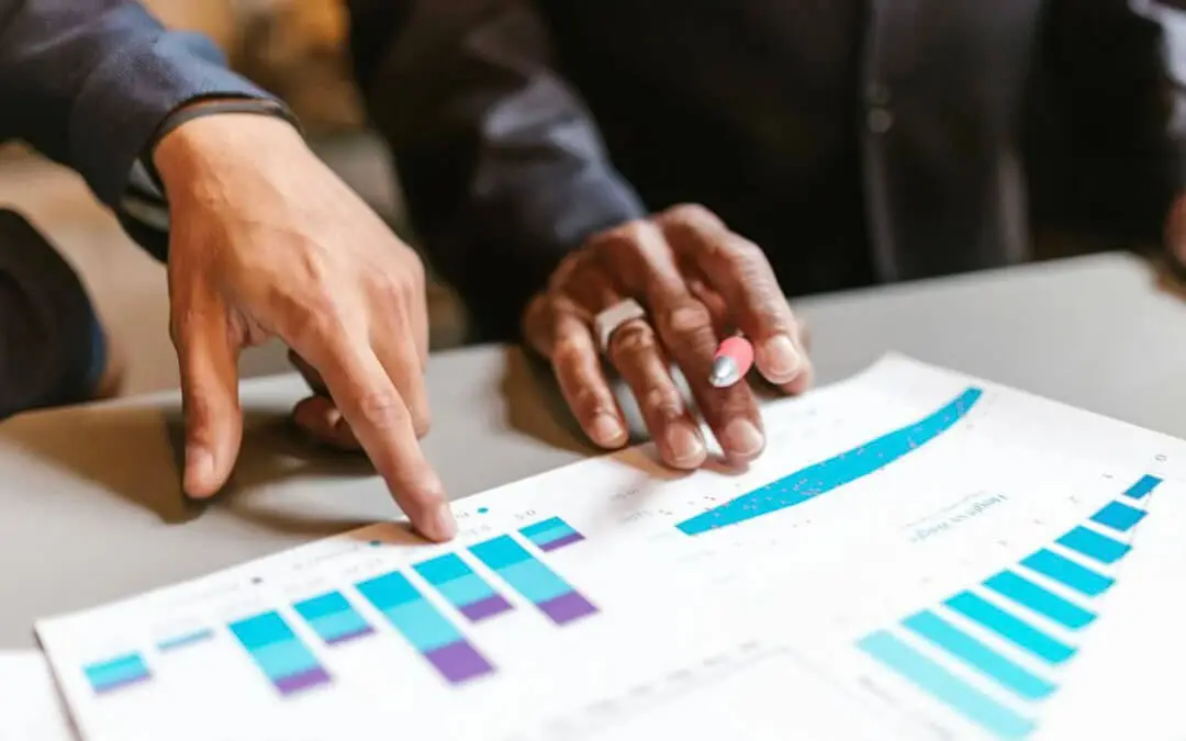 mãos de dois homens apontando resultados em gráficos no papel