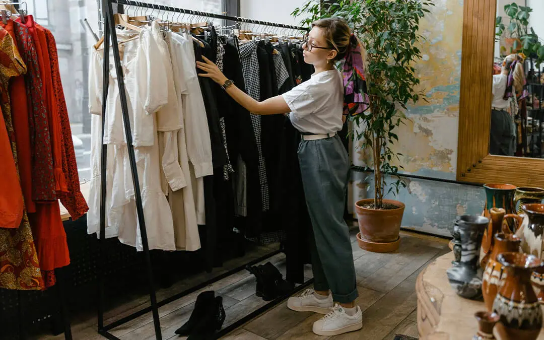 mulher organizando roupas em arara de loja