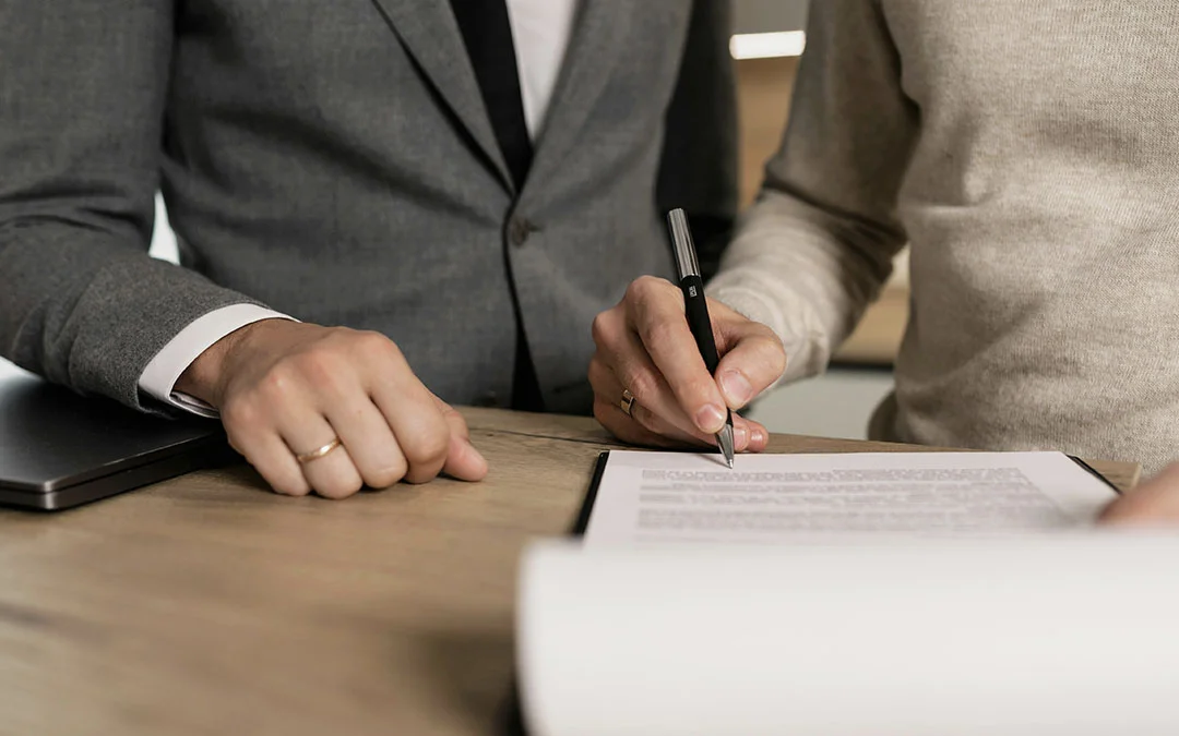 mulher assinando documentos ao lado de homem