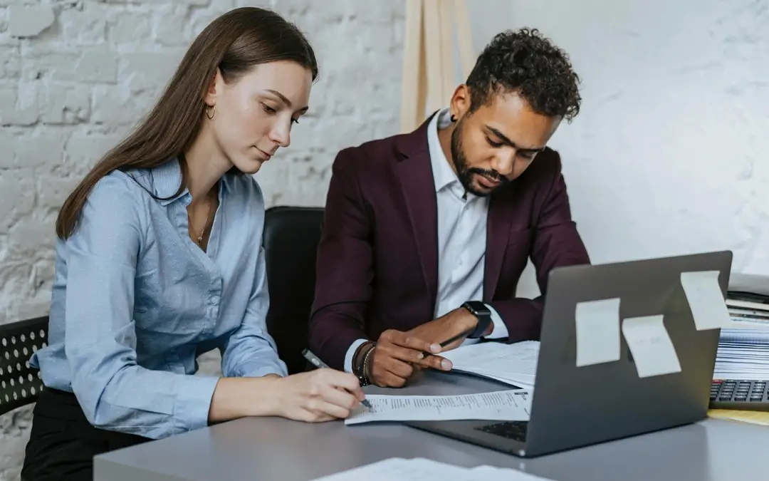 mulher e homem em mesa de escritório olhando papéis