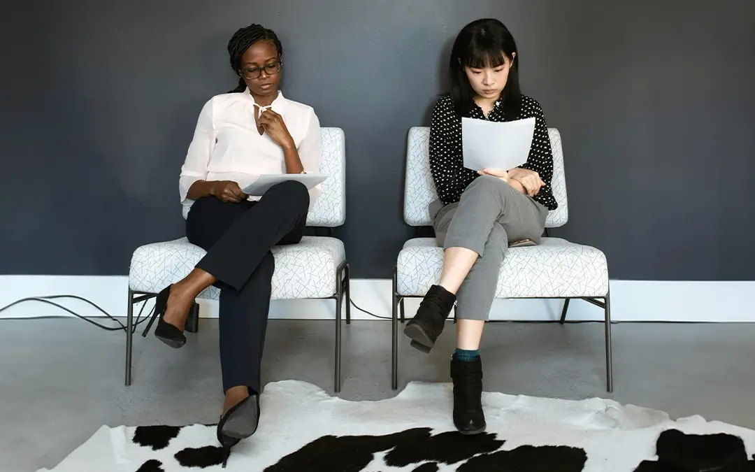 duas mulheres sentadas lendo declaração de comparecimento