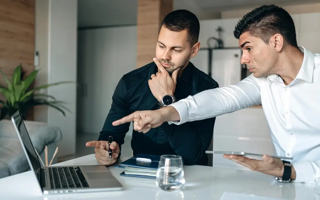 homem apontando para laptop enquanto outro homem olha