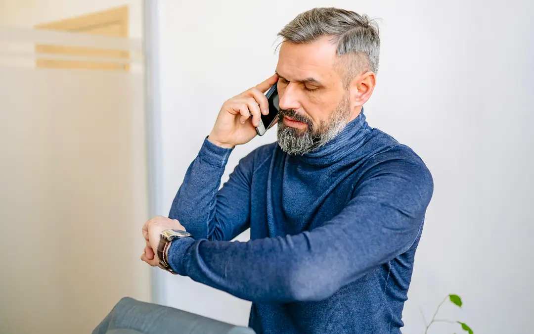homem de meia idade no celular olhando para o relogio