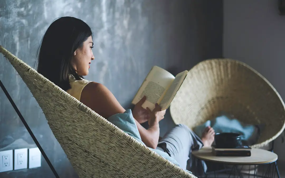 mulher sentada em poltrona lendo um livro