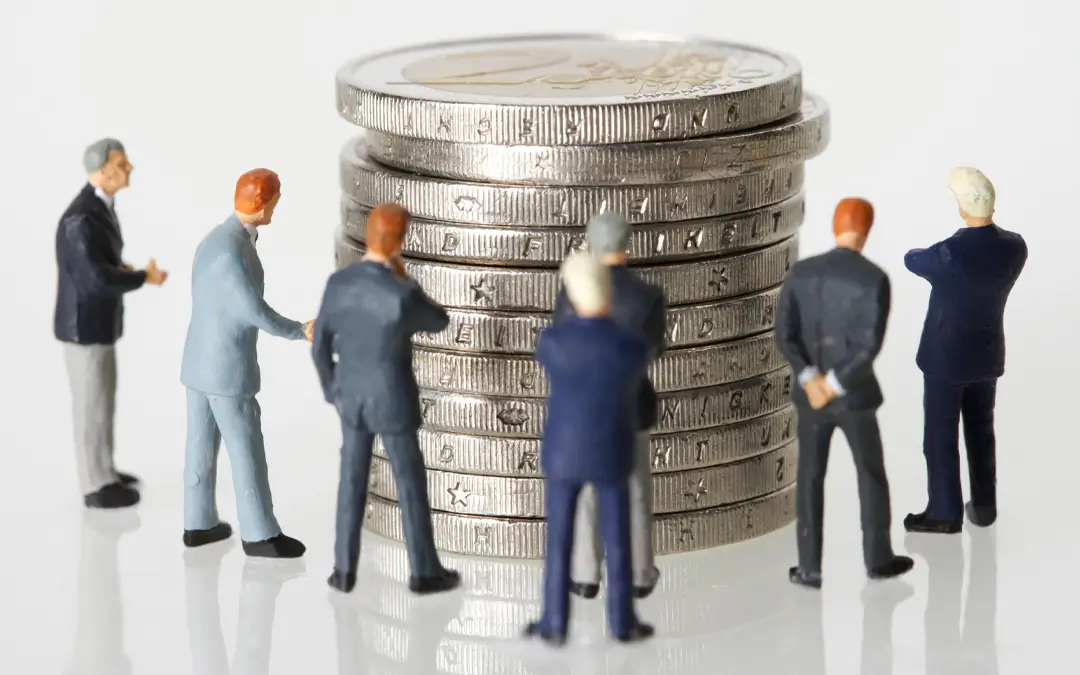 miniatura de bonecos ao redor de moedas emplihadas
