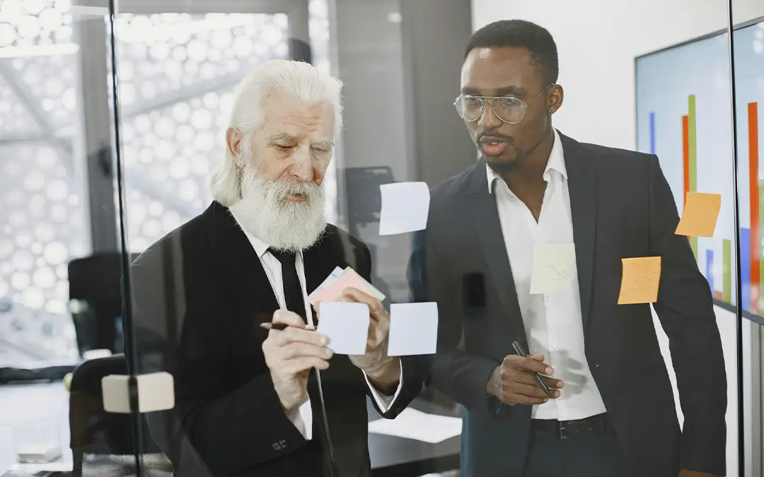 idoso fazendo mapa mental com apoio de colega de trabalho