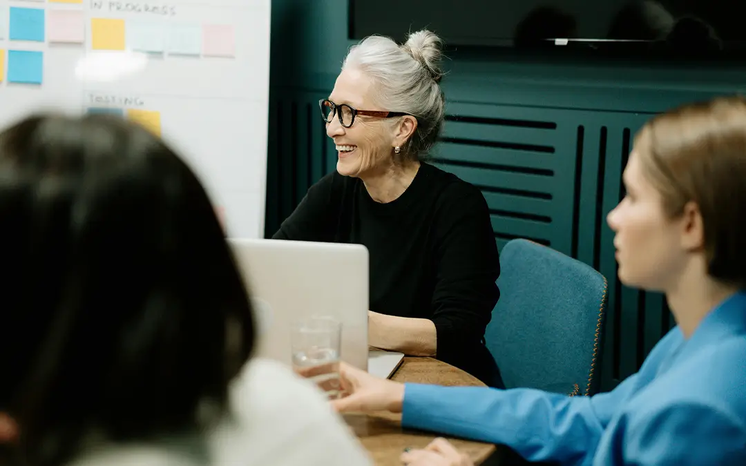mulher idosa sorrindo em reunião com colegas de trabalho