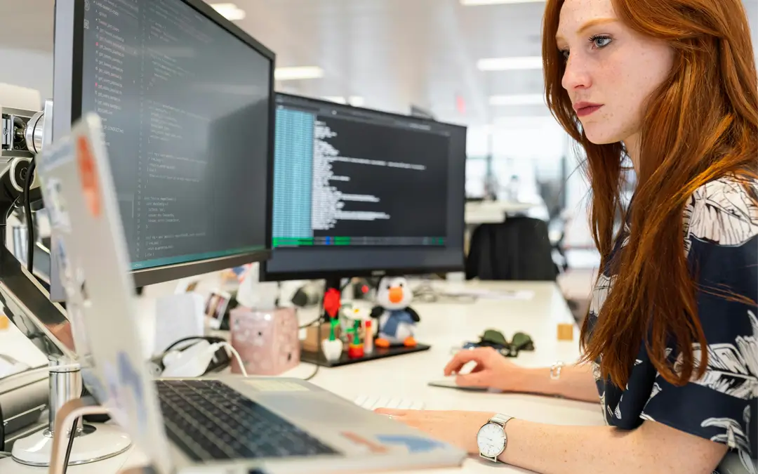 mulher do TI trabalhando com dois monitores