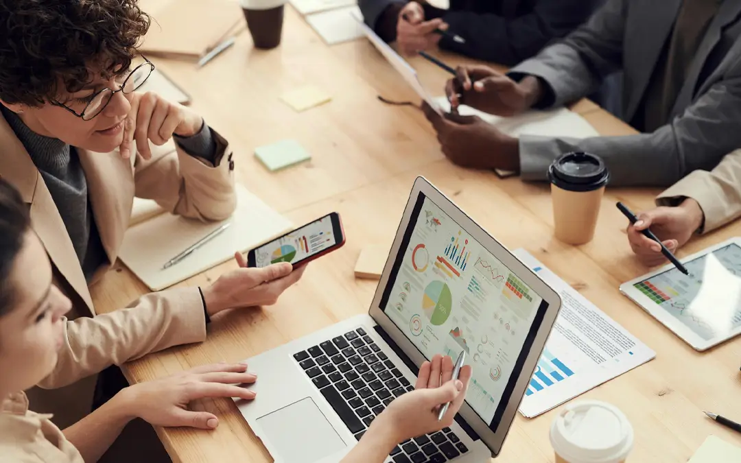 mulheres analisando gráficos em laptop com equipe ao redor