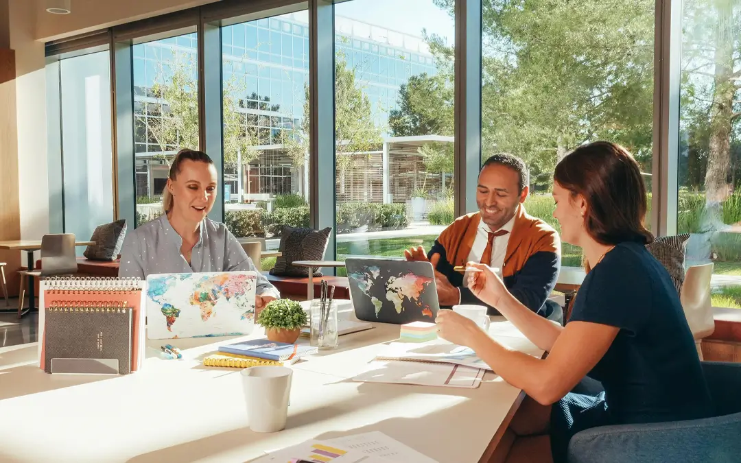 três colegas de trabalho sorrindo descontraídos no escritório