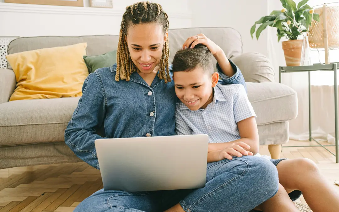 mão e filho sentados na sala olhando laptop
