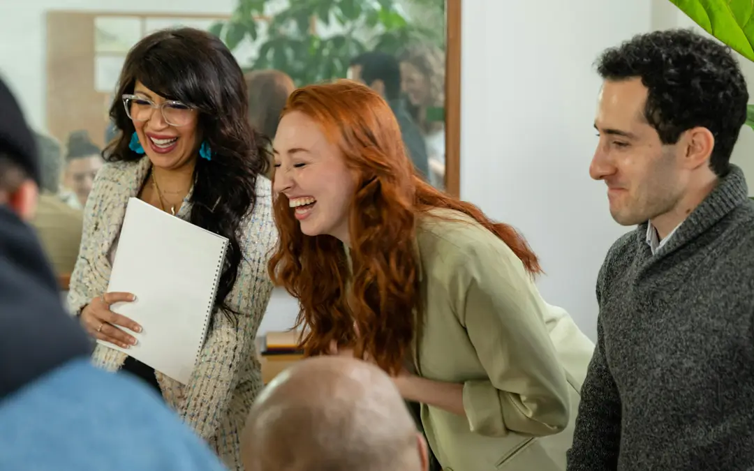 mulher rindo em meio a colegas de trabalho em reunião descontraída