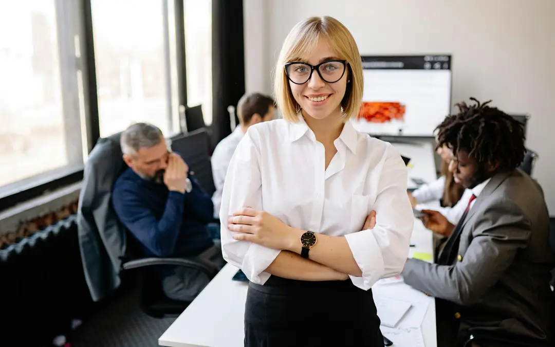 mulher executiva de rh sorrindo com equipe atrás no escritório