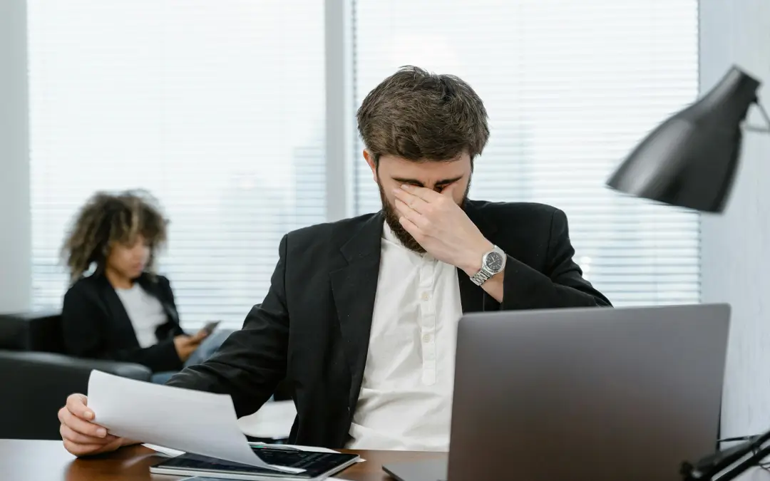 funcionário com mão nos olhos cansado em sua mesa de trabalho