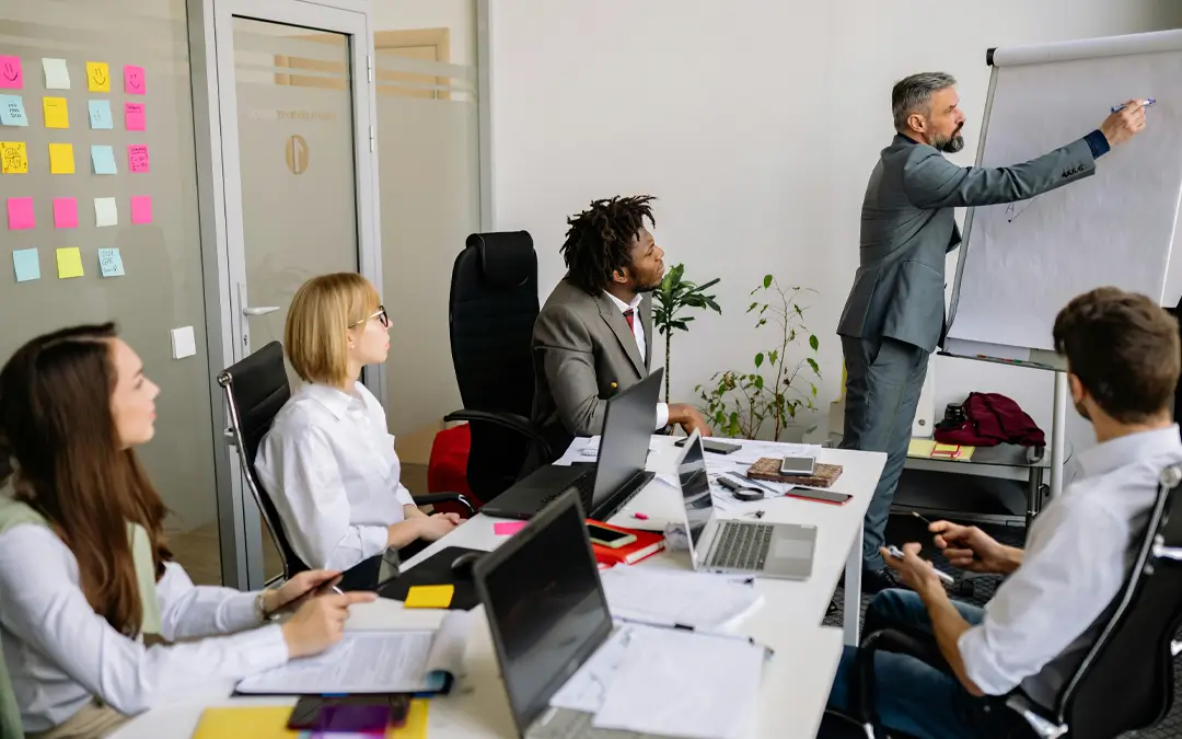 equipe em reunião com líder escrevendo no flipchart