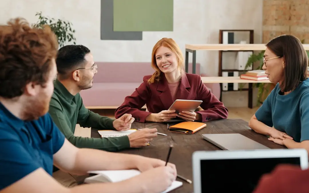 mulher ruiva sorrindo em reunião com equipe de trabalho