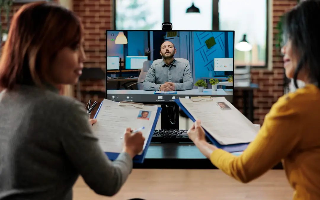 duas mulheres fazendo entrevista de emprego com candidato em reunião pelo computador