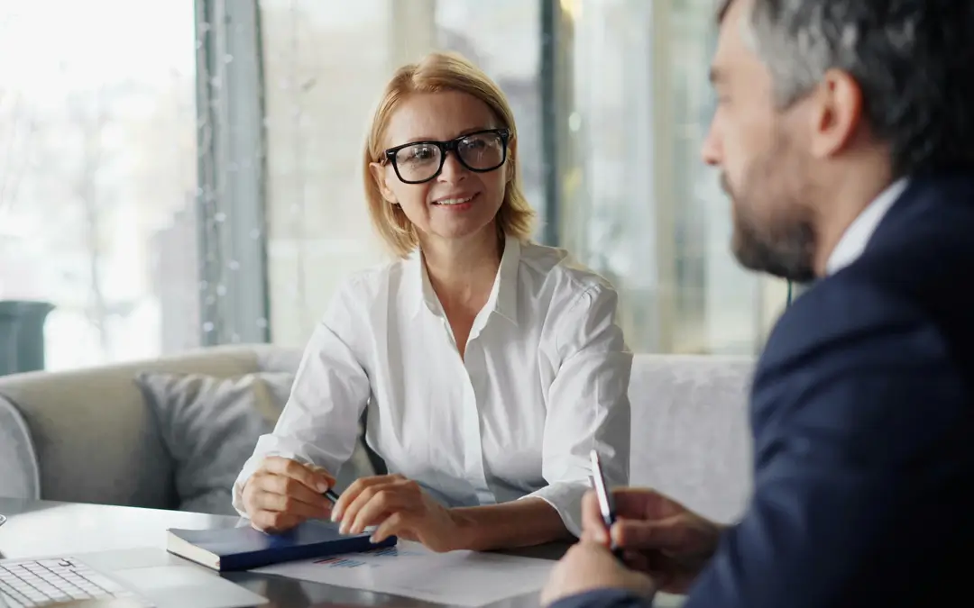 mulher de meia idade sorrindo enquanto conversa com homem na mesa de um escritório