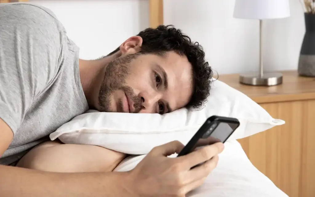 homem deitado olhando o celular