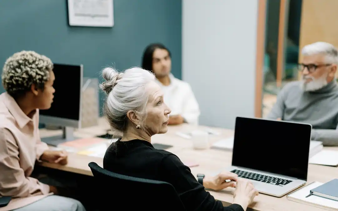 mulher de meia idade no laptop em reunião com equipe jovem