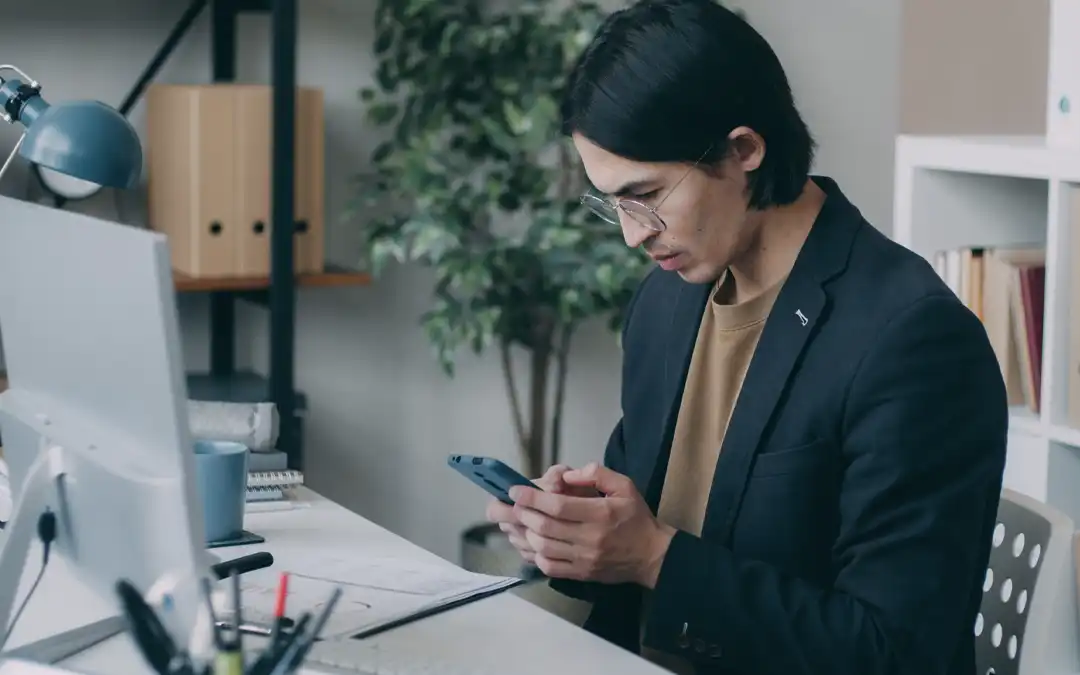 Jovem olhando o celular enquanto trabalha em home office