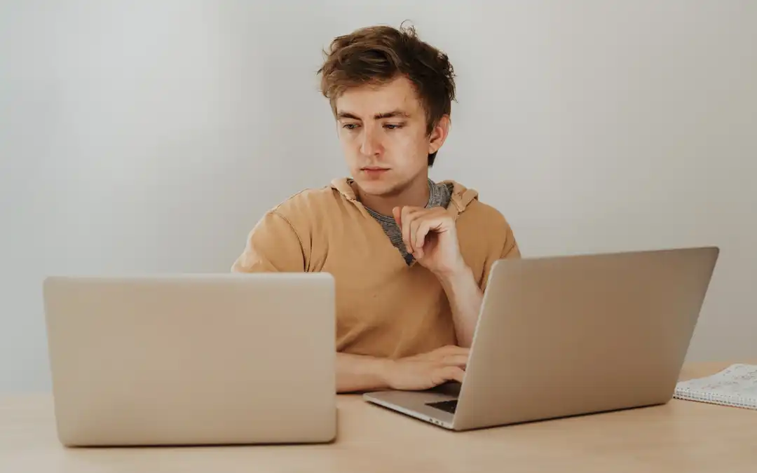 jovem com dois laptops abertos